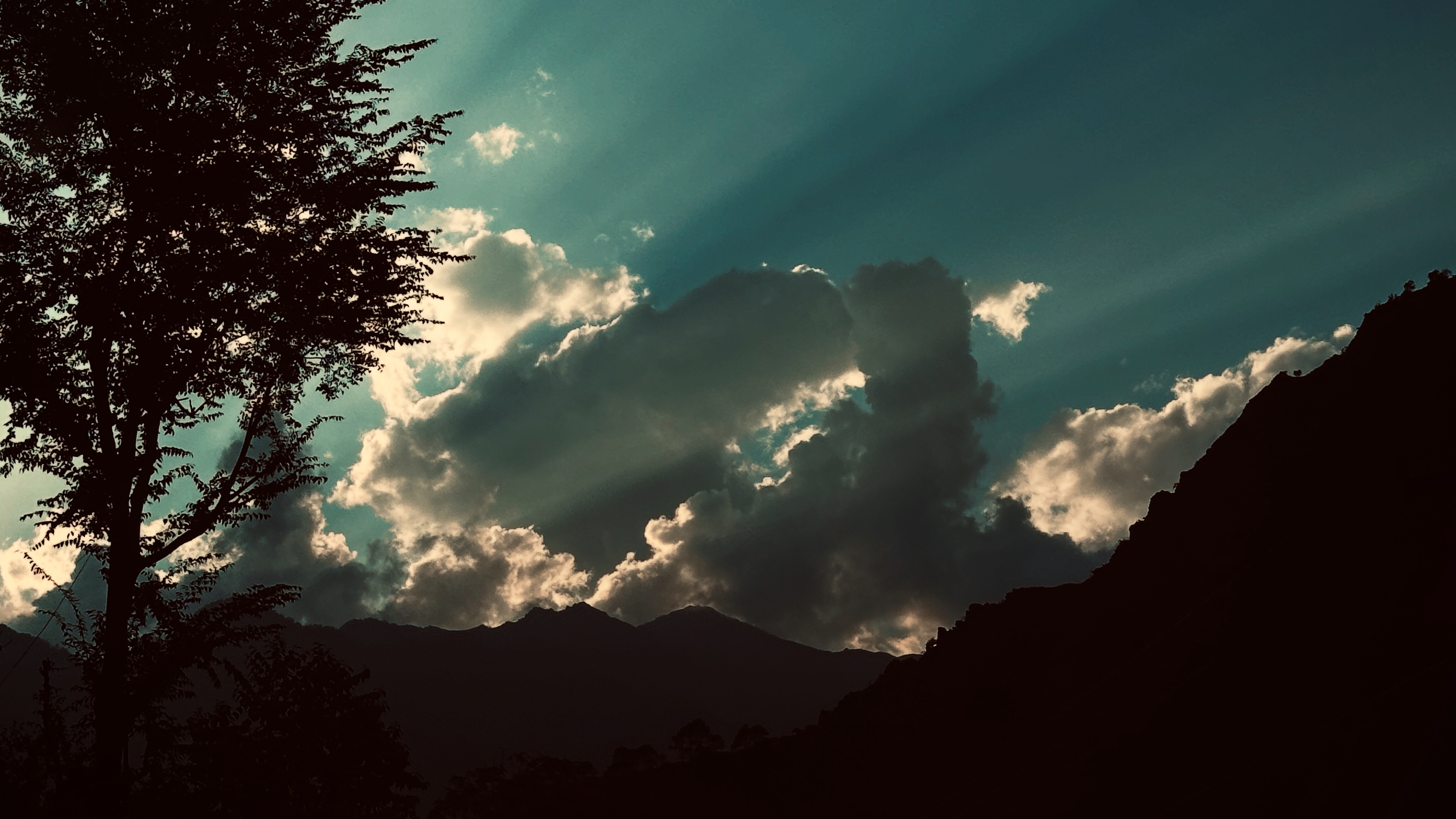 Sun rays breaking through clouds over the Auli mountain silhouette